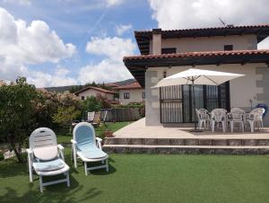 a group of chairs and an umbrella on a lawn at Chalet independiente con vistas in Bustarviejo