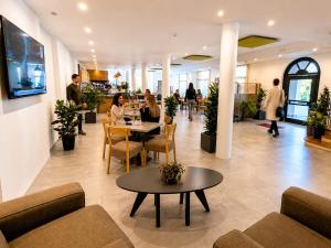 a lobby with people sitting at tables in a restaurant at Hotel Vela in Nago-Torbole