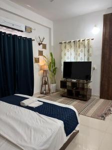 a living room with a bed and a flat screen tv at The Cozy Petals in Gaya