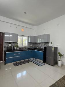 a large kitchen with blue cabinets and a refrigerator at The Cozy Petals in Gaya +8 photos