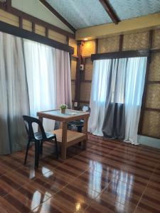 a table and chairs in a room with white curtains at Henalric's Place in Roxas