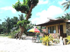 a house on the beach with a table and an umbrella at Henalric's Place in Roxas