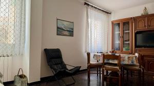 a living room with a chair and a table and a television at A Due Onde, Viola Mare in Alassio