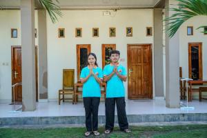 a man and woman standing in front of a house praying at Golo Tango Homestay in Labuan Bajo