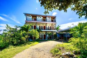 a house on a hill with a dirt road in front at Golo Tango Homestay in Labuan Bajo