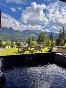 a pool of water with two chairs and a table at Villa La Roca Garden & Spa ADULTS ONLY in Kościelisko