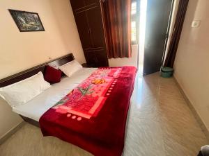 a bedroom with a bed with a red blanket on it at Himalayan Wellness Retreat in Rishīkesh