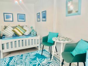 a bedroom with a crib and two chairs and a table at A Heavenly View in Muizenberg