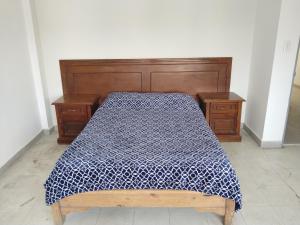 ein Bett mit einer blau-weißen Bettdecke in der Unterkunft Hostal Batarse Centro in Torreón