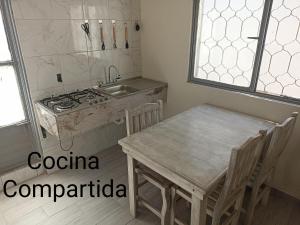 eine Küche mit Tisch, Herd und Spüle in der Unterkunft Hostal Batarse Centro in Torreón