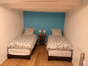 two beds in a room with blue walls at Maison de charme a moye in Moye