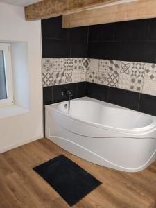 a white bath tub in a bathroom with black tiles at Maison de charme a moye in Moye