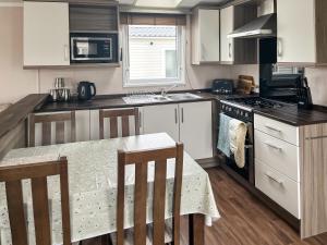 a kitchen with a table and a stove top oven at Pebbles in Pakefield