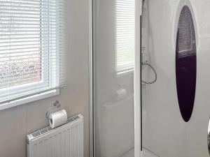 a bathroom with a shower and a toilet and a window at Pebbles in Pakefield