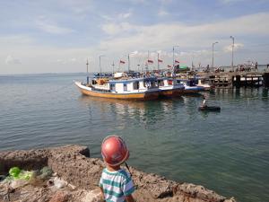 a young boy looking at a boat in the water at Amanda Ekas Homestay in Pulau Gilkaliantan