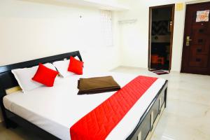 a bedroom with a bed with red and white pillows at Mercury JKR Residency in Yelagiri