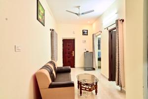 a living room with a couch and a glass table at Mercury JKR Residency in Yelagiri