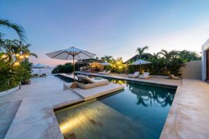 an infinity pool with chairs and umbrellas at a resort at Private Oceanfront Villa Kingfisher - 20m Infinity Pool in Nusa Lembongan