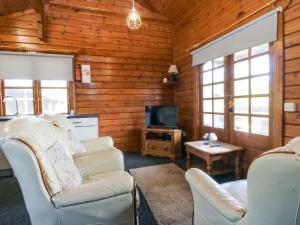 a living room with two chairs and a television at Lodge 1 - Bron Eifion in Criccieth