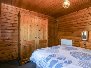 a bedroom with a bed in a wooden cabin at Lodge 1 - Bron Eifion in Criccieth
