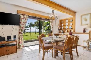 a dining room with a table and chairs and a television at Hale Kamāoa Naalehu in Naalehu