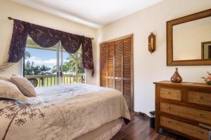 a bedroom with a bed and a window and a dresser at Hale Kamāoa Naalehu in Naalehu
