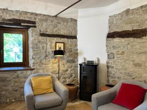 a living room with two chairs and a stone wall at Villa delle Fonti - Villa With Pool in Toano