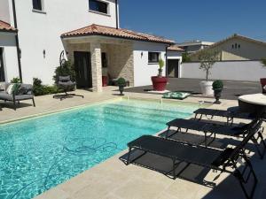 a swimming pool with two chairs and a house at Villa avec piscine jacuzzi et sauna in Saint-André-de-Cubzac