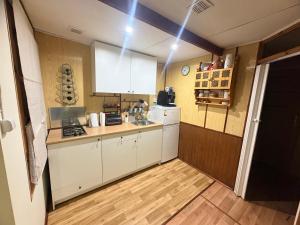 a kitchen with white cabinets and a wooden floor at Letnisko na Pierkunowie in Giżycko +26 photos