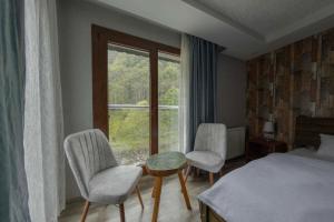 a bedroom with a bed and two chairs and a window at Elikti Otel in Ardeşen