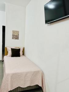 a bedroom with a bed with a tv on the wall at Voer Jequitibá Hospedaria in Jequitibá