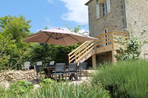 a table and chairs under an umbrella in a garden at Camping and Gîtes - Le Mas d'Ayen in Ayen