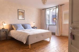 a bedroom with a bed with blue pillows and a window at Camping and Gîtes - Le Mas d'Ayen in Ayen