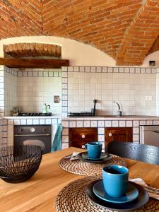 a kitchen with a wooden table with two blue cups on it at B&B Casa Oleandro in Chiaverano +14 photos