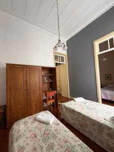 a bedroom with two beds and a table and a chair at Casarão Cidade Imperial in Petrópolis