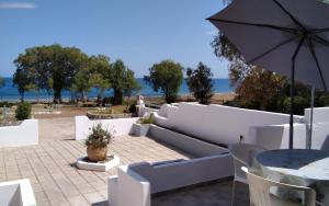 a white patio with a table and an umbrella at Endless BLUE Lahania in Lachania