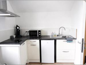 a white kitchen with a sink and a microwave at Bienvenue à Saint Julien De Vouvantes - Dormir Comme A La Maison in Saint-Julien-de-Vouvantes