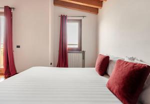 a white bed with red pillows in a bedroom at Villa Mattei Franciacorta in Villa Pedergnano