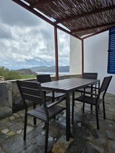 a wooden table and chairs on a patio with a view at Spitaki Milos in Tripiti