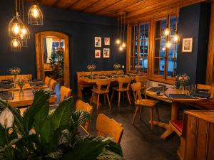 a dining room with tables and chairs and lights at Hotel Restaurant Jungfrau in Lauterbrunnen