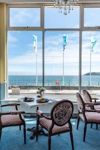 a room with a table and chairs and a view of the ocean at The Queens Hotel in Penzance