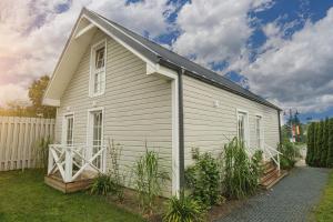 a small white house with a fence in a yard at Prance namai in Plateliai