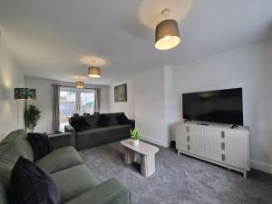 a living room with a couch and a flat screen tv at Spacious 3 Bedroom House with Large Drive in Dundee +8 photos