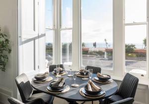 a dining room with a table and chairs and windows at 3 Bedroom, 3 bathroom large flat with sea views! in Hastings