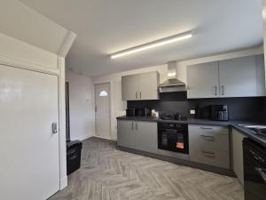 a kitchen with white cabinets and black counter tops at Spacious 3 Bedroom House with Large Drive in Dundee