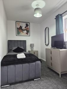 a bedroom with a large bed and a television at Spacious 3 Bedroom House with Large Drive in Dundee