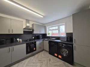 a kitchen with white cabinets and a washer and dryer at Spacious 3 Bedroom House with Large Drive in Dundee
