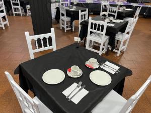 ein schwarzer Tisch mit weißen Tellern und Servietten darauf in der Unterkunft Hostal Baviera in Pesués