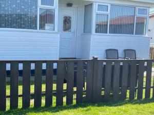 a house with two chairs in front of a fence at Chalet 147 South Shore Bridlington in Bessingby +4 photos