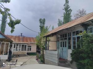 an old house with a man standing outside of it at Guesthouse Shakirbek in Arslanbob